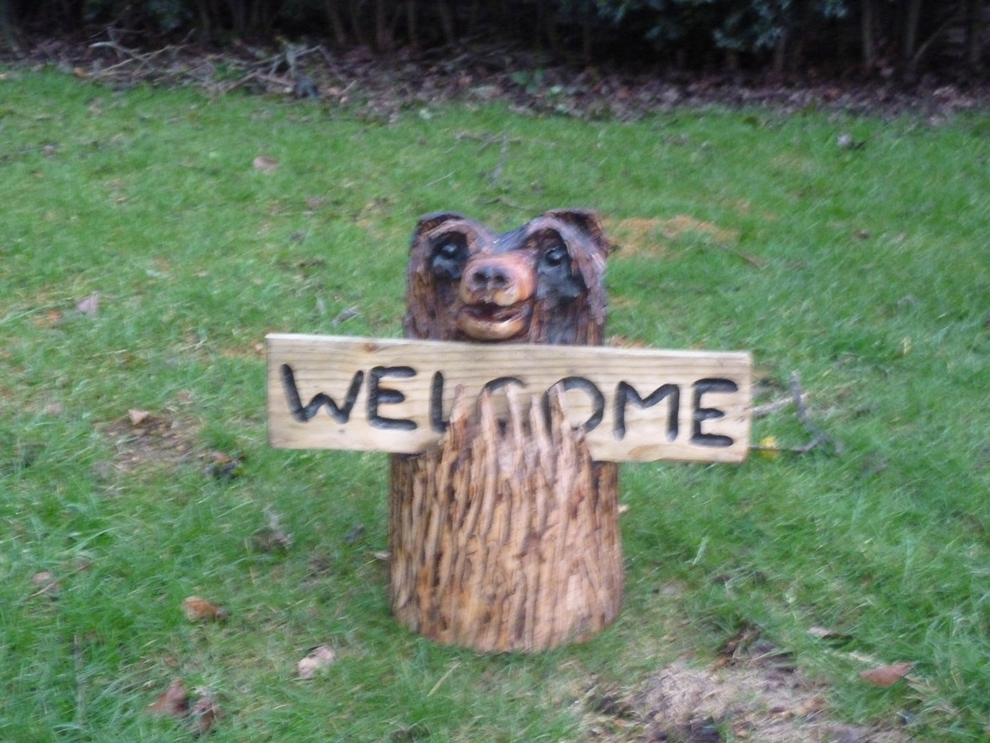 Chainsaw Carved Bear in a log with a welcome sign